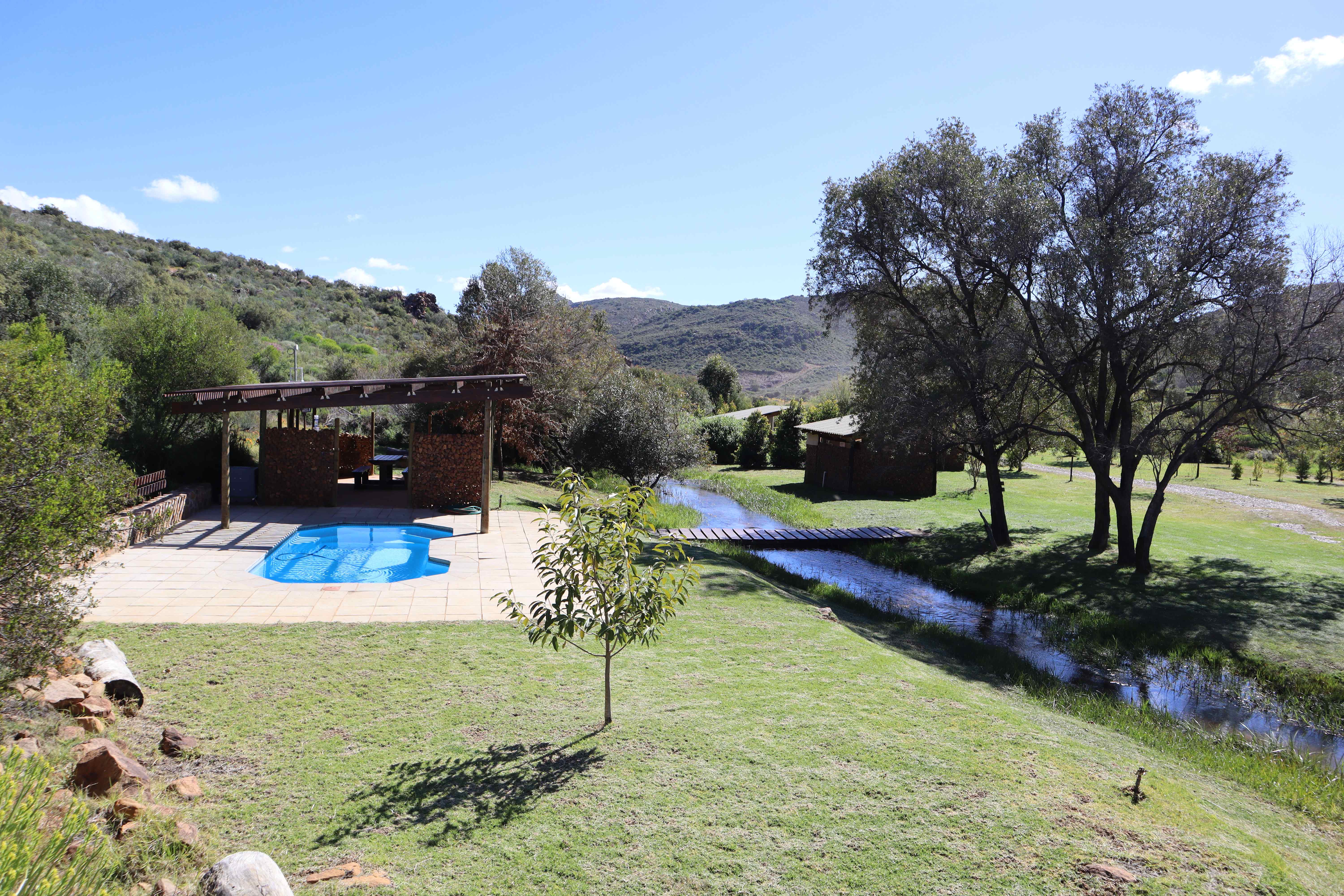 Swimming pool area with lapa and natural stream running through the campsite